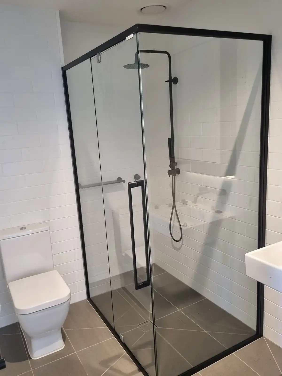 Semi-frameless shower screen with brushed nickel hardware in a Melbourne bathroom